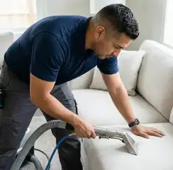Professional upholstery cleaning technician using an extraction wand to deep-clean a fabric sofa, Minneapolis, MN.